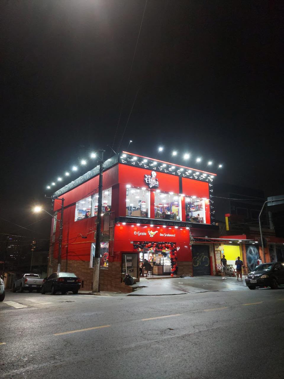 Fachada iluminada à noite, com salão do segundo andar visível pelas vidraças